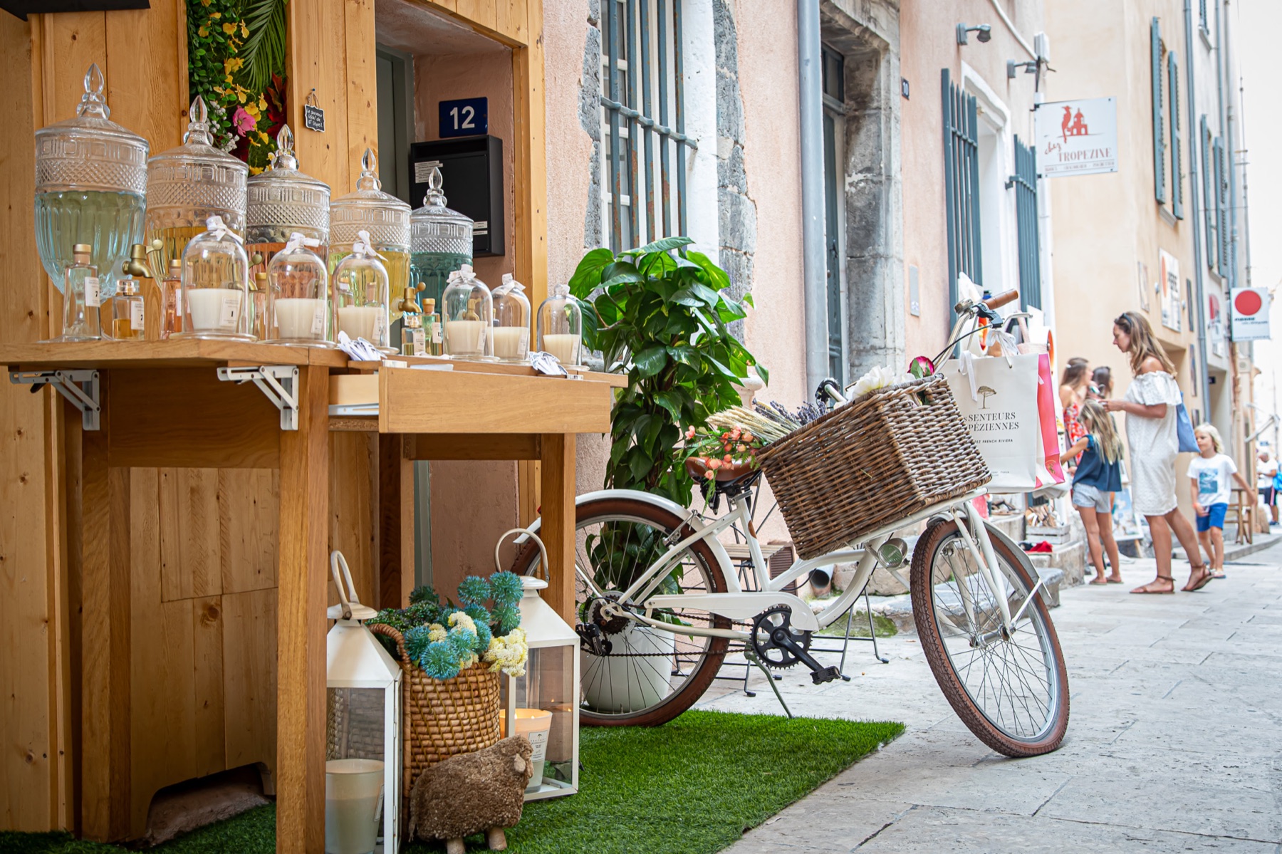 Winkel met glazen flessen en een fiets met rieten mand in een winkelstraat