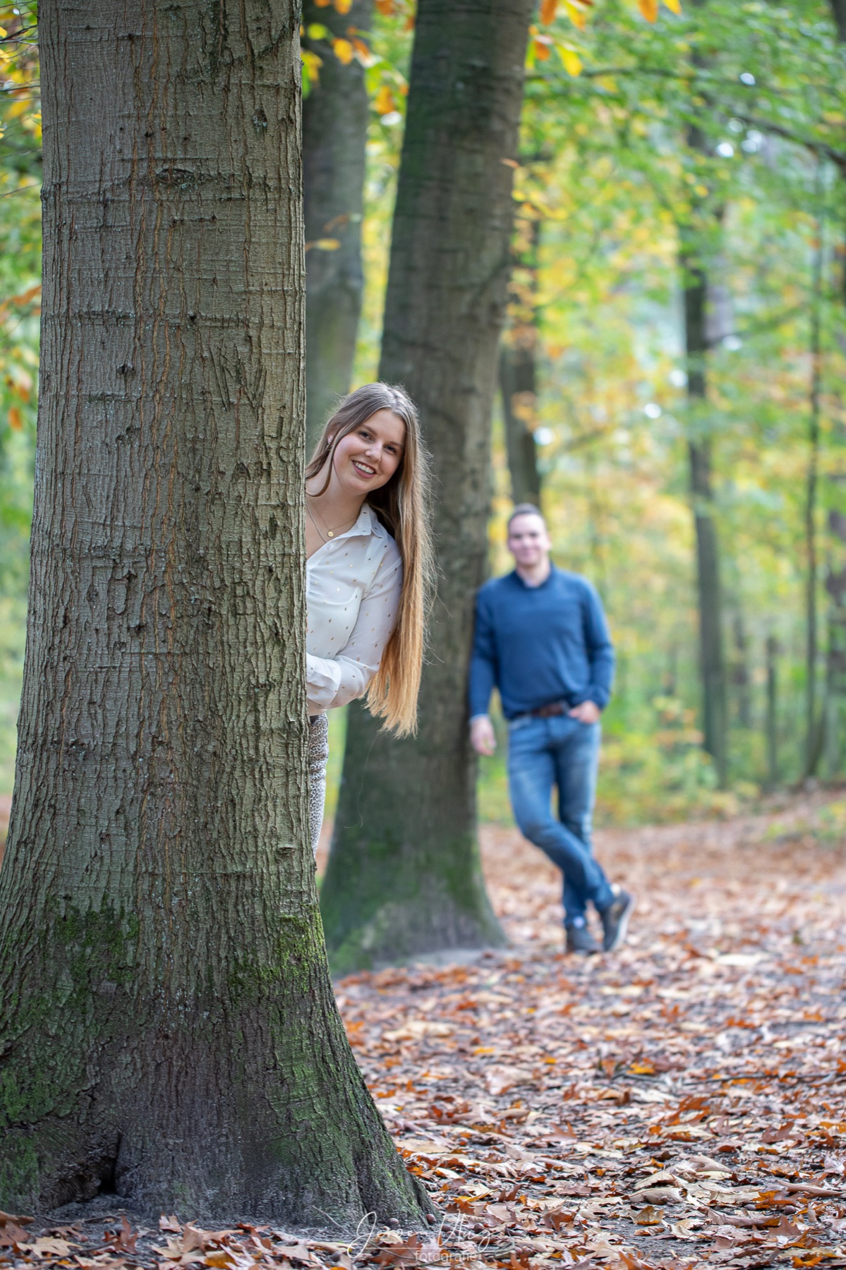 Twee mensen tussen de bomen in een herfstbos