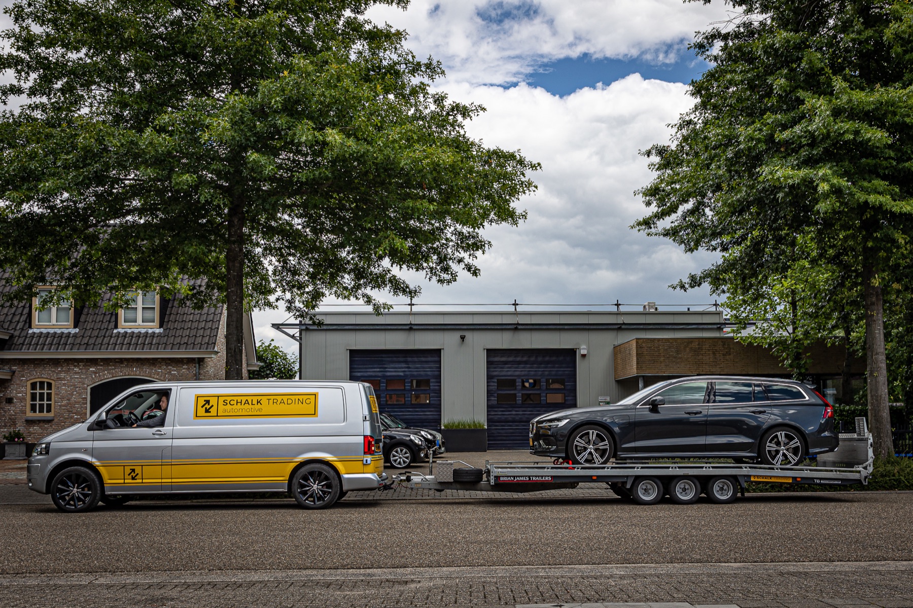 Bedrijfsbus met een auto op een aanhanger